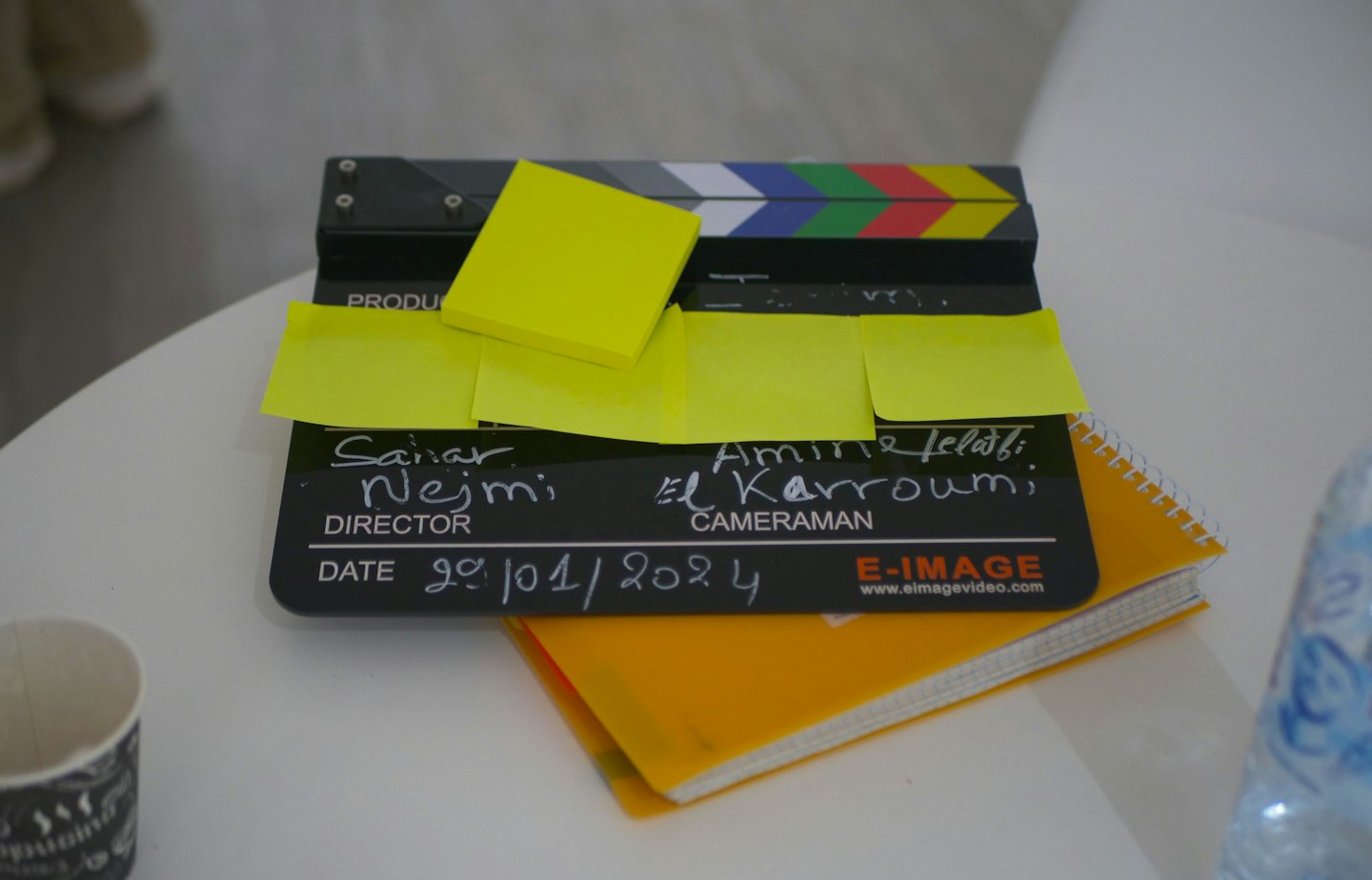 Claqueta de cine con notas adhesivas sobre un cuaderno.